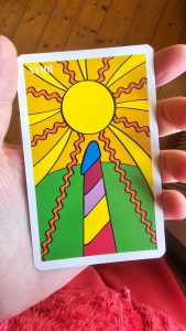 photo of an intuiti card, with a stylised rainbow phallus and a bright sun and a green hill
